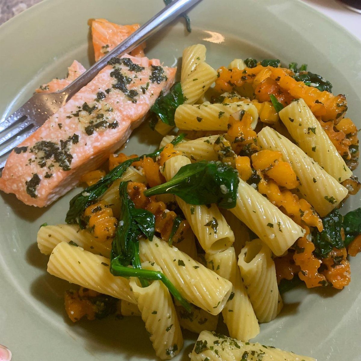 Pesto topped salmon fillet served with rigatoni pasta, spinach, and diced vegetables.