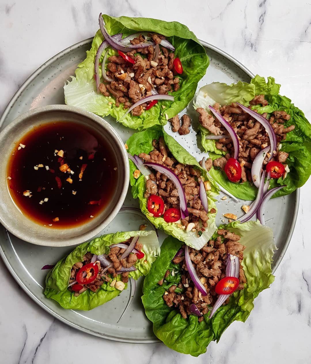 Pork lettuce wraps with red onion and chili served with dipping sauce.