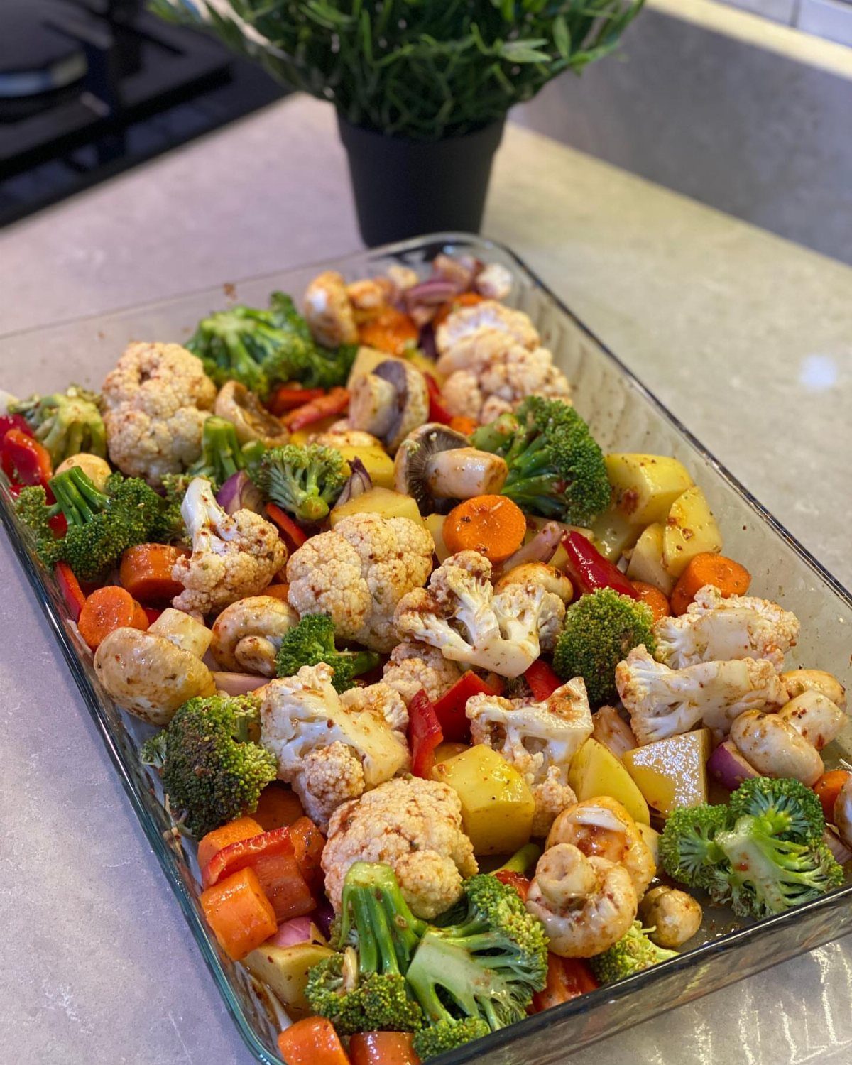 Roasted cauliflower, broccoli, carrots, and peppers in a clear glass baking dish.