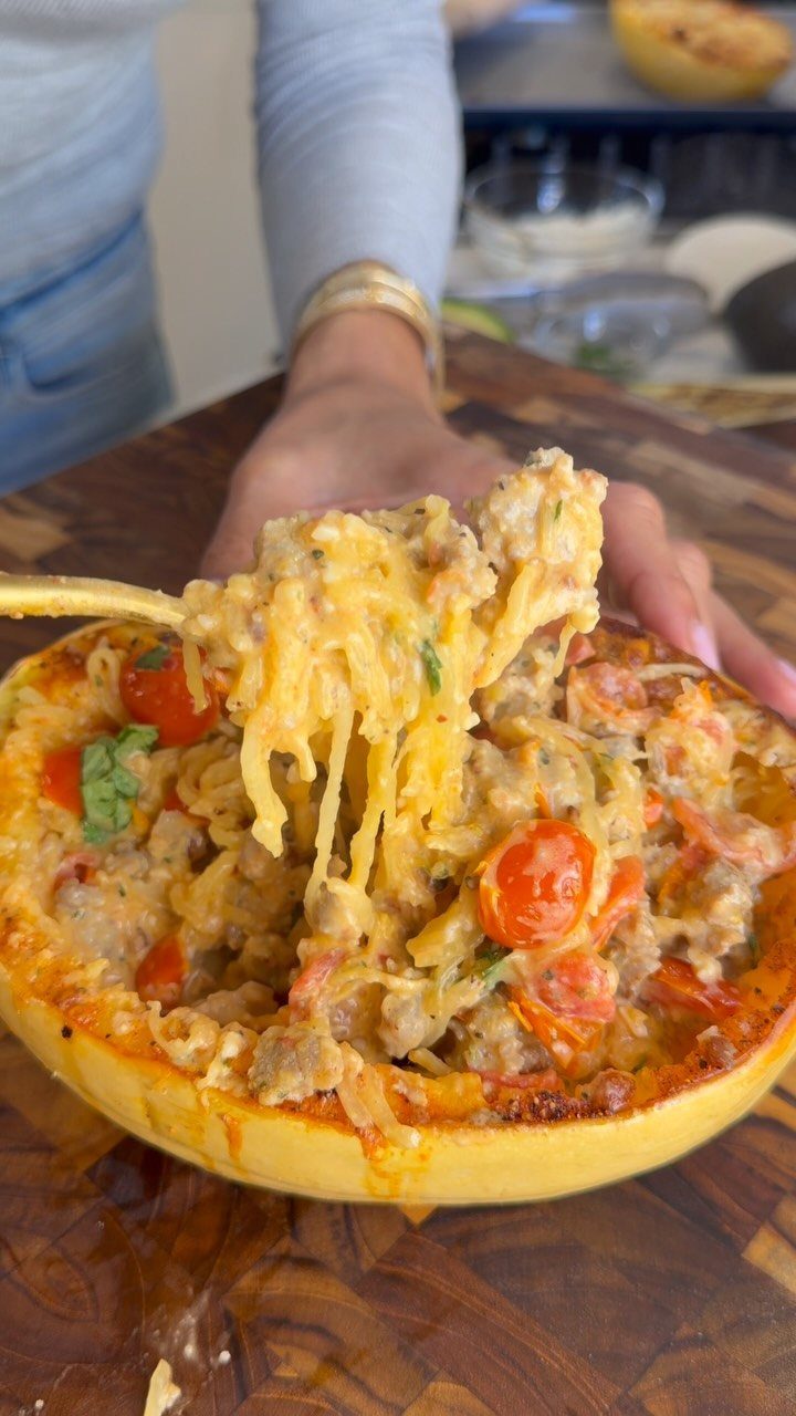 Stuffed spaghetti squash half filled with cheesy meat and cherry tomatoes on wooden board