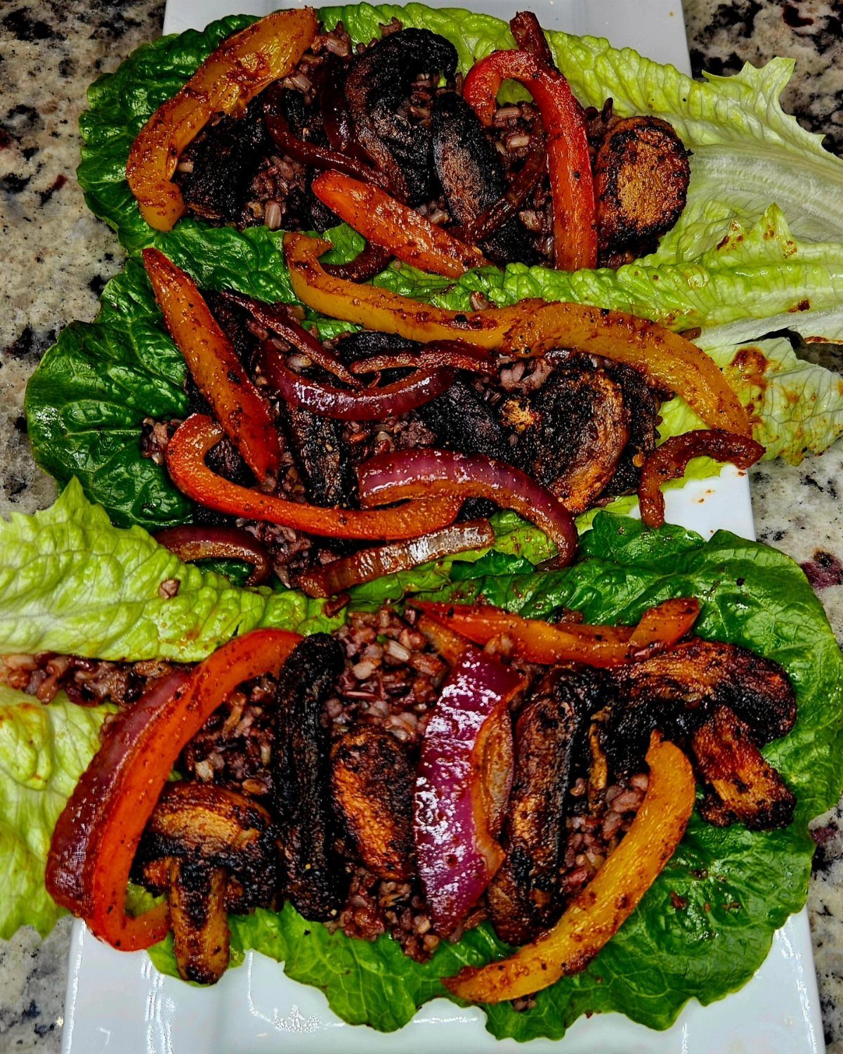 Lettuce wraps filled with sautéed bell peppers, mushrooms, red onions, and grains.