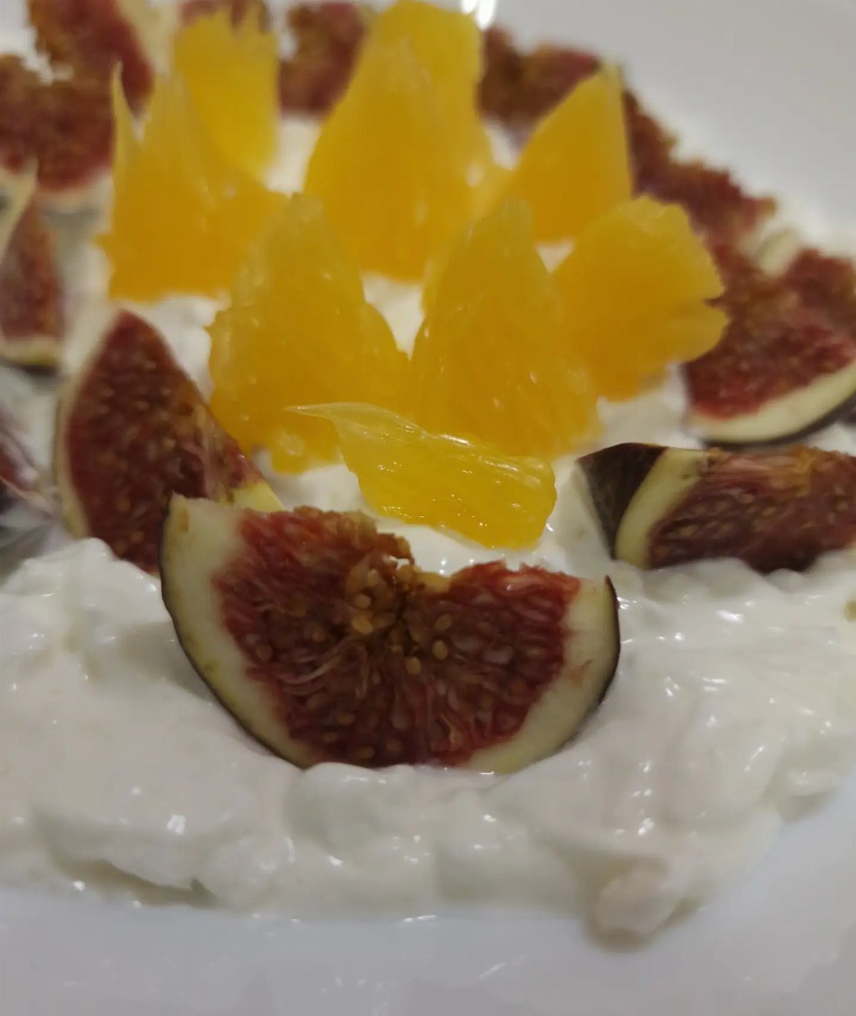 Cottage cheese topped with fresh orange segments and sliced figs on a white plate.