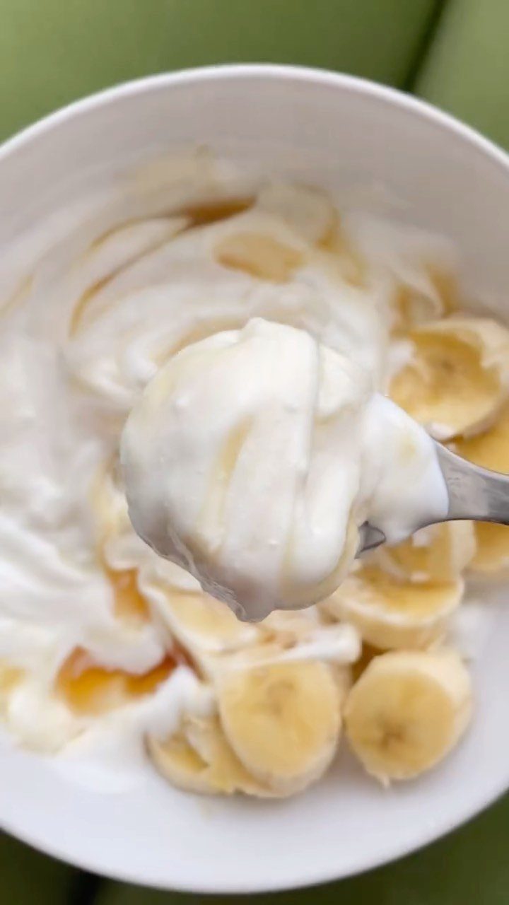 Greek yogurt with honey and sliced bananas in a white bowl.