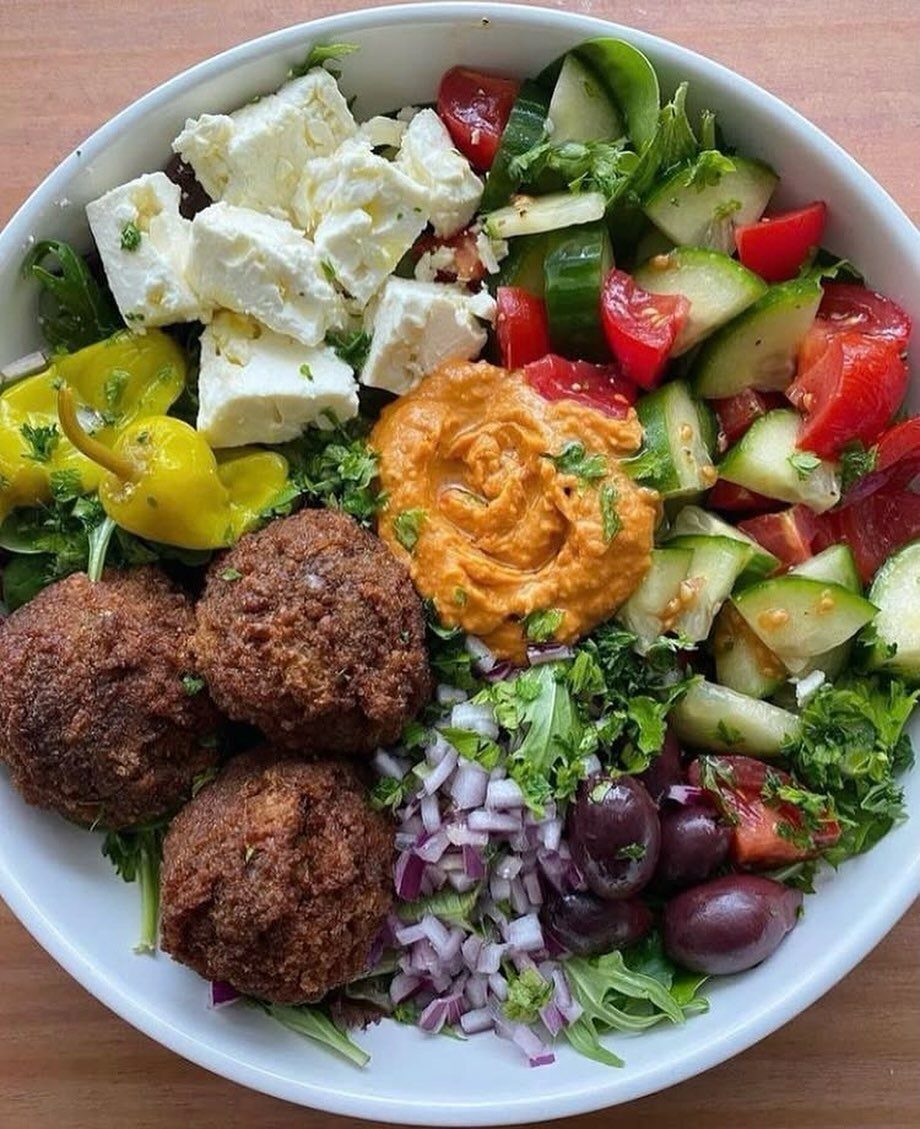 Mediterranean bowl with falafel, hummus, feta cheese, cucumbers, tomatoes, and olives.