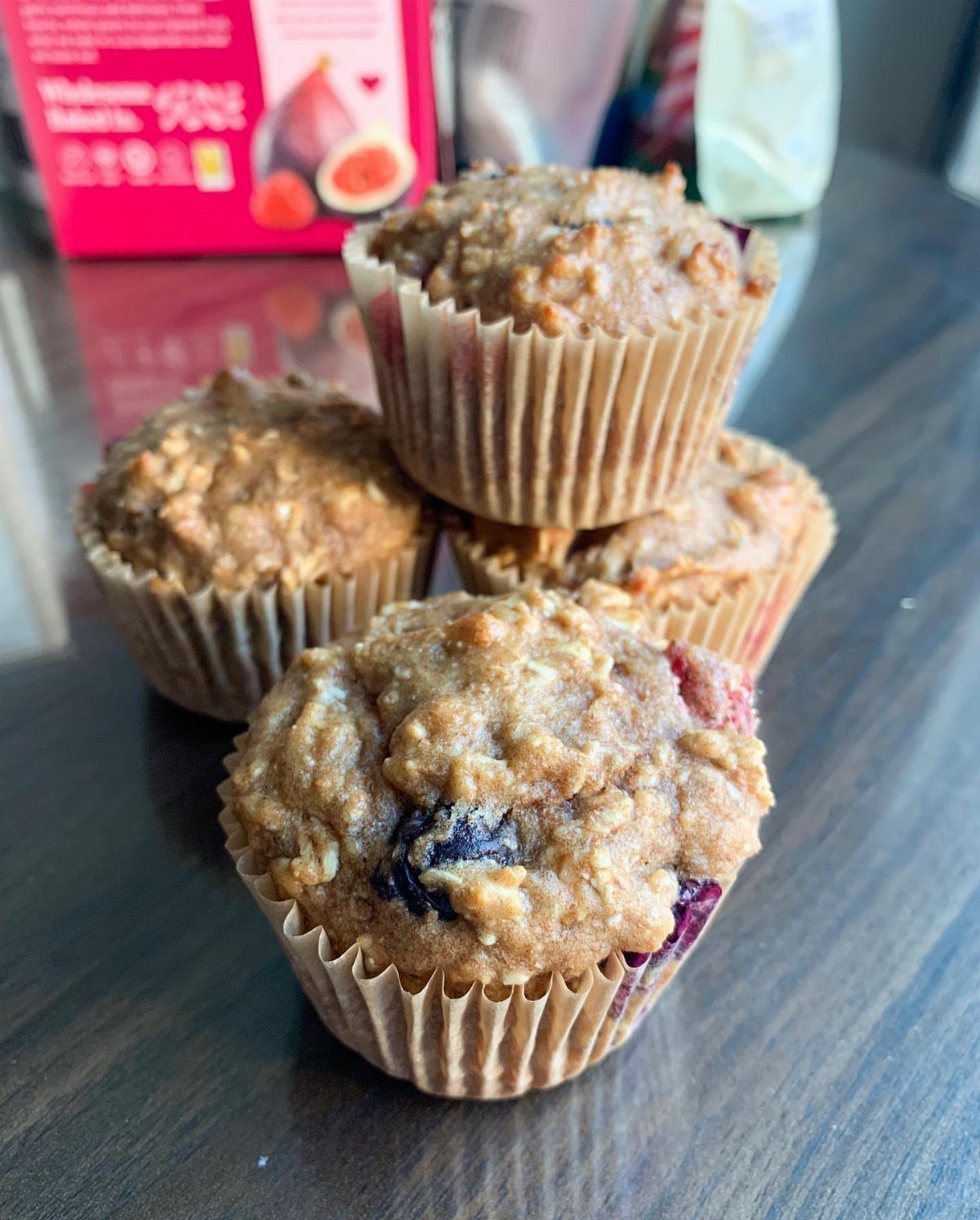 21 Healthy Mini Snacks for Lunchboxes, Parties and Busy Days 18 Four small oat and berry muffins stacked on a dark wooden table.