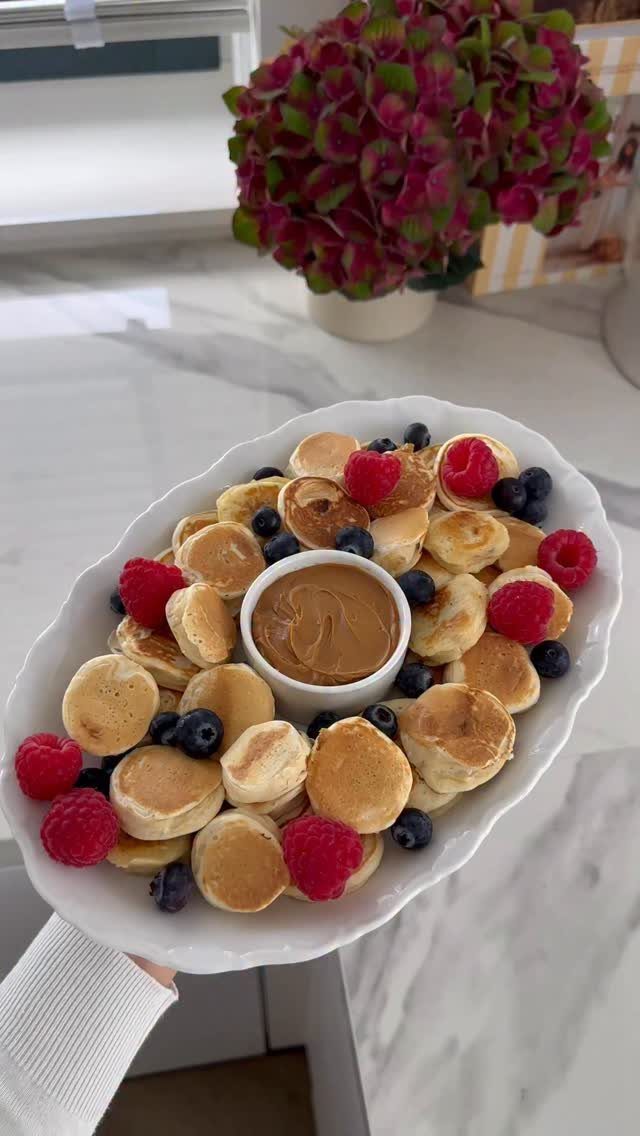 21 Healthy Mini Snacks for Lunchboxes, Parties and Busy Days 22 Mini pancakes with raspberries, blueberries, and nut butter on a white platter.