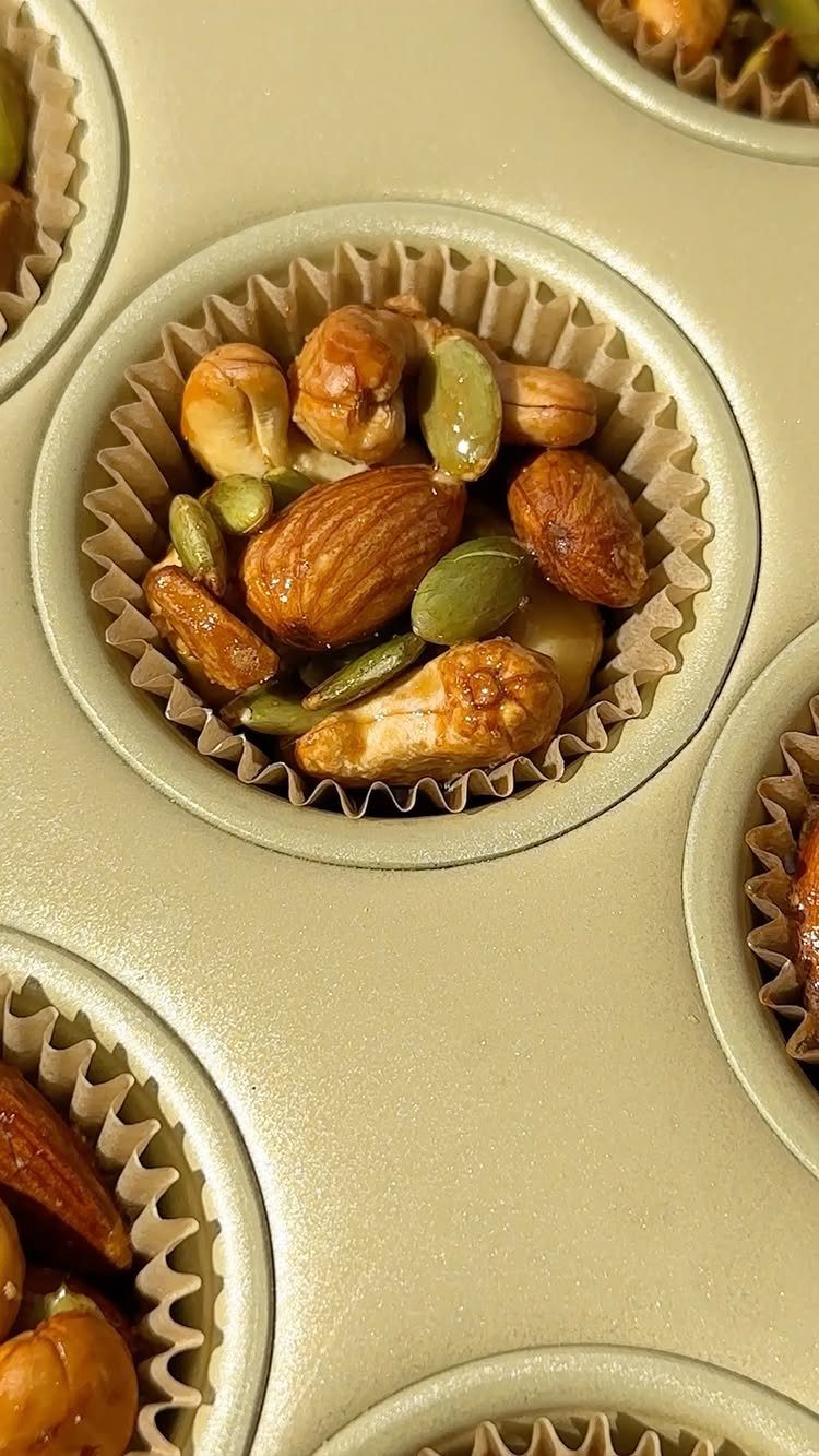 21 Healthy Mini Snacks for Lunchboxes, Parties and Busy Days 12 Mixed nuts and pumpkin seeds in small paper liners inside a muffin tin.