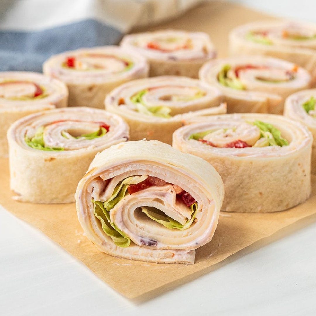 21 Healthy Mini Snacks for Lunchboxes, Parties and Busy Days 10 Turkey rollups with lettuce and red pepper on brown parchment paper.
