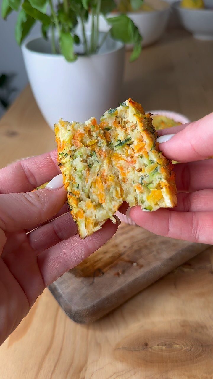 21 Healthy Mini Snacks for Lunchboxes, Parties and Busy Days 9 Zucchini and carrot muffin broken in half held by two hands over wood.