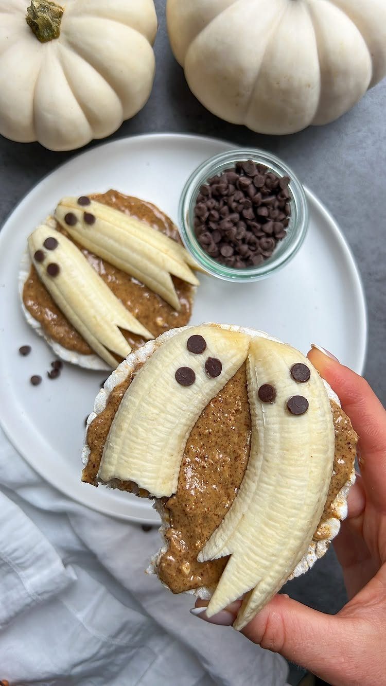 Rice cakes topped with nut butter and banana slices shaped like ghosts.