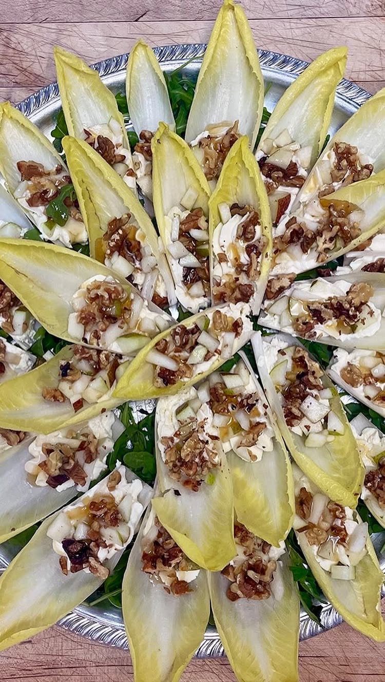 Endive boats filled with cream cheese, apples, and nuts on a silver platter.