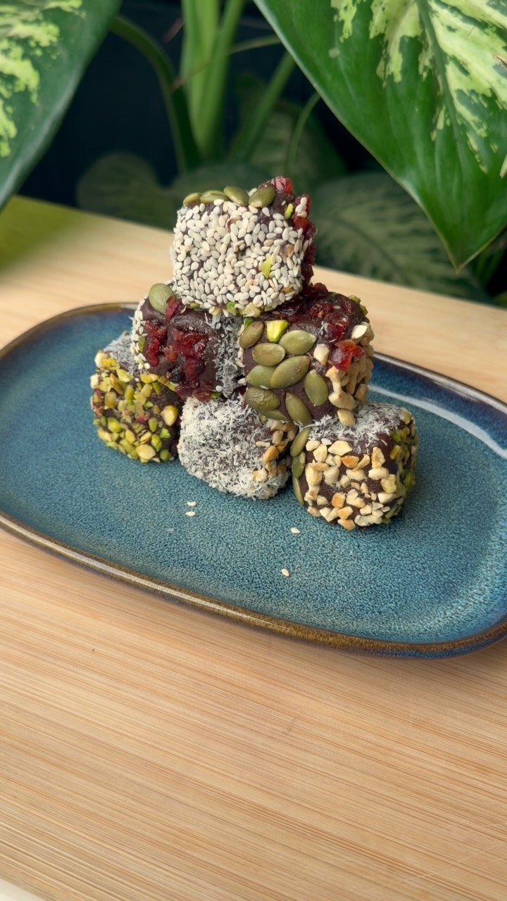 Stacked energy bites with coconut, seeds, and nuts on a blue ceramic plate.
