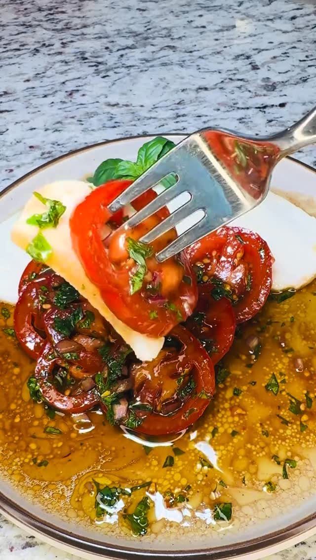 Sliced tomatoes and mozzarella cheese with oil and herbs on a white plate
