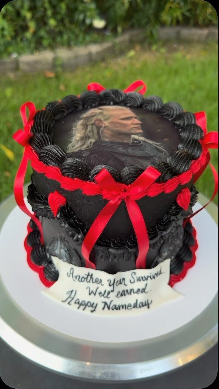 Black House of the Dragon cake with edible portrait and red ribbon accents.
