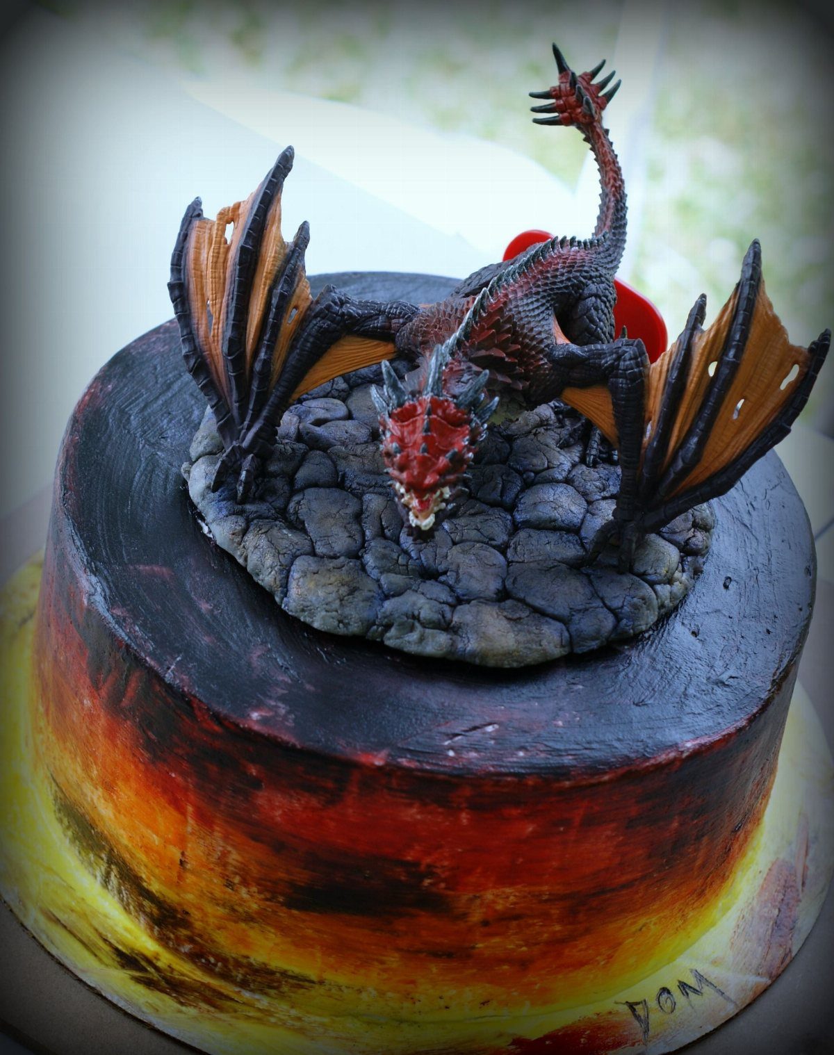 Dragon figurine on a stone-textured cake with red and orange gradient sides.