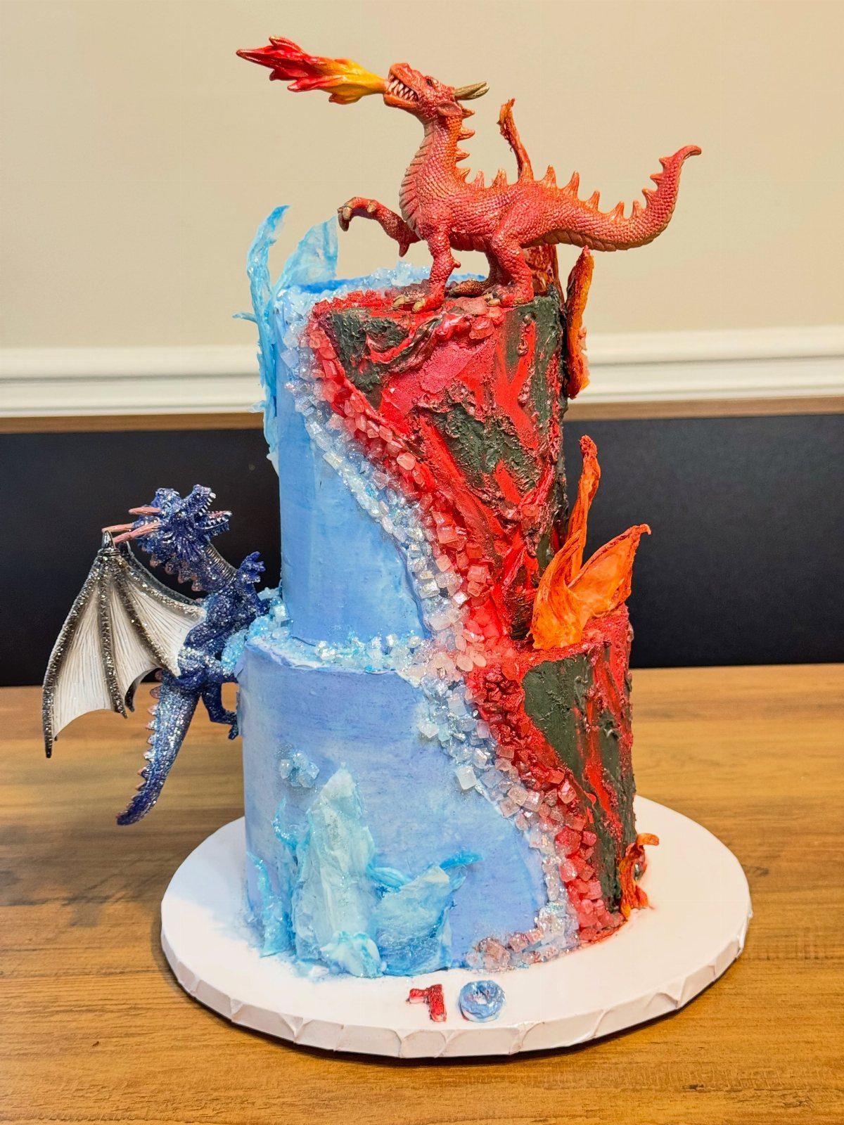 Two-tier cake split into red and blue with fire and ice dragon figures.