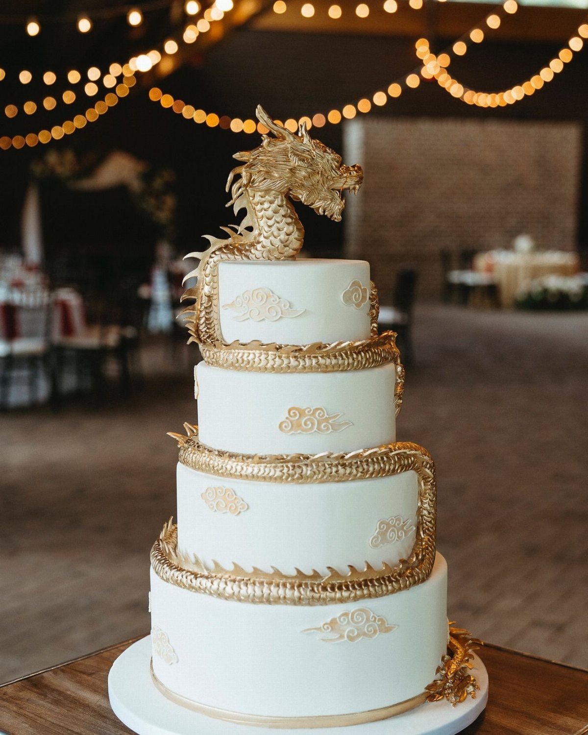 Four-tier white cake with a golden dragon winding around it and a dragon topper.