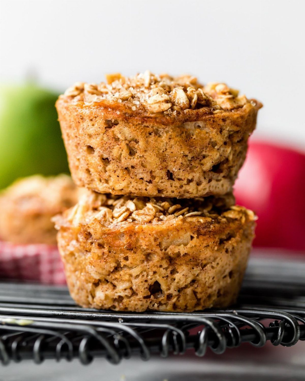 16 Morning Healthy Breakfast Ideas, From Egg Bites to Oats 8 Two baked oatmeal cups stacked on a black wire cooling rack with apples behind.