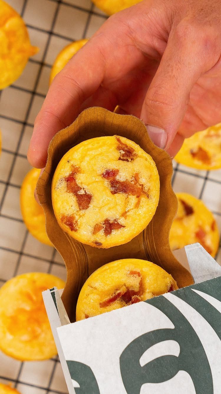 16 Morning Healthy Breakfast Ideas, From Egg Bites to Oats 2 Hand holding a cardboard carrier with two round bacon egg bites over a rack.