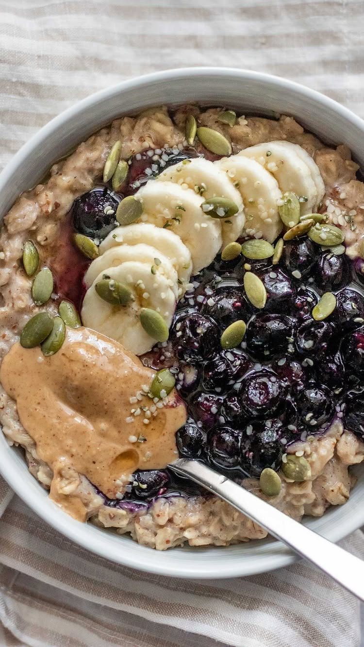 16 Morning Healthy Breakfast Ideas, From Egg Bites to Oats 4 Oatmeal bowl topped with banana slices, blueberries, nut butter, and pumpkin seeds.