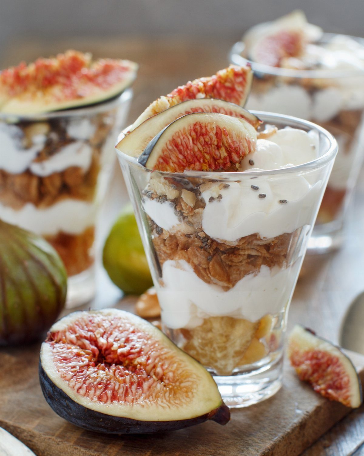 Fruit parfaits with layers of yogurt, granola, and fresh sliced figs in glass cups.