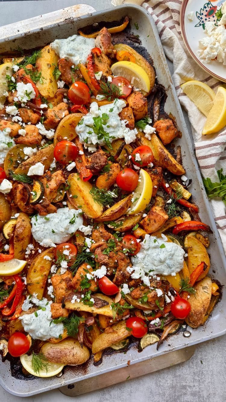 Roasted chicken and potatoes with tomatoes and tzatziki on a sheet pan