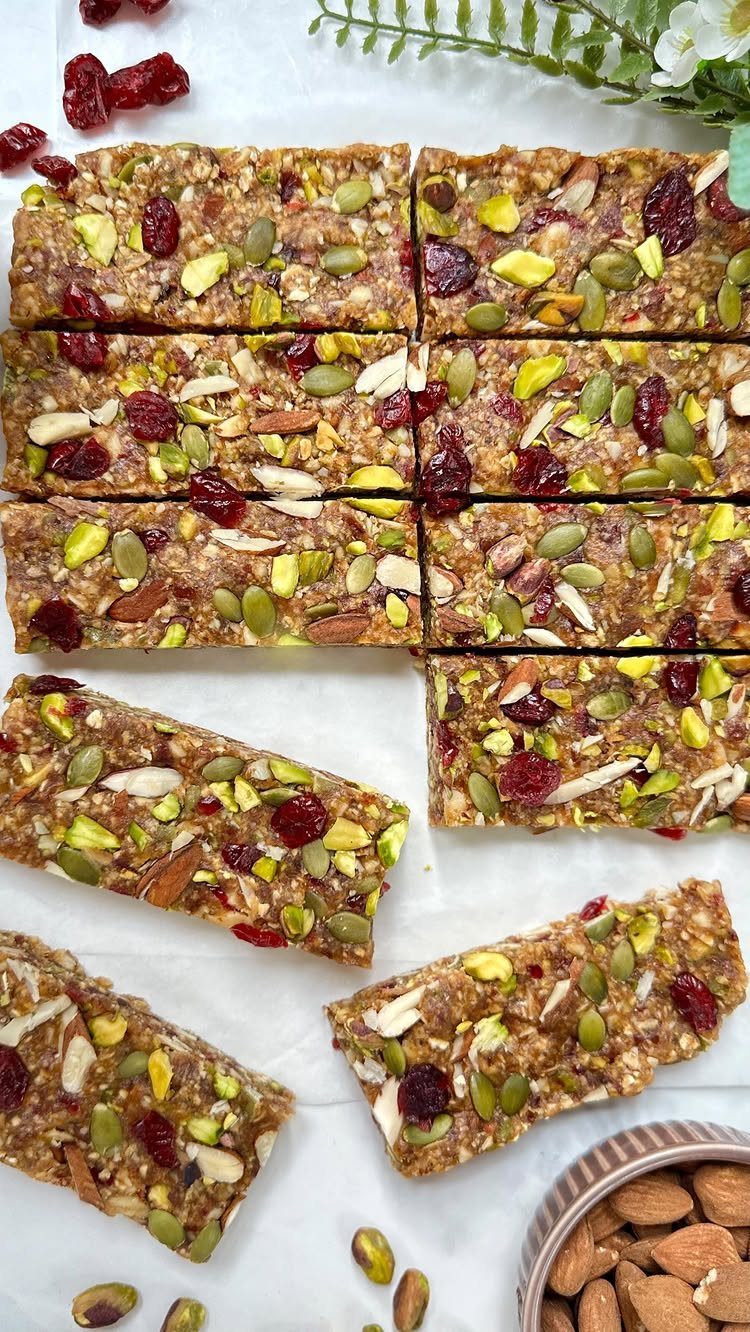 Granola bars with dried cranberries and mixed nuts on white parchment paper.