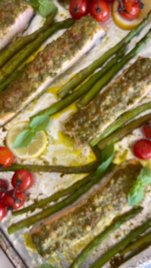 Pesto topped salmon fillets baked with asparagus, cherry tomatoes, and lemon slices.