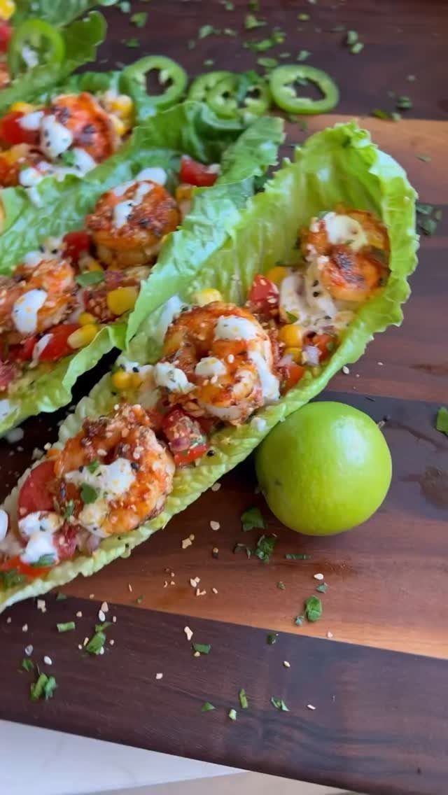 Shrimp lettuce wraps with corn and creamy sauce on a wooden board.