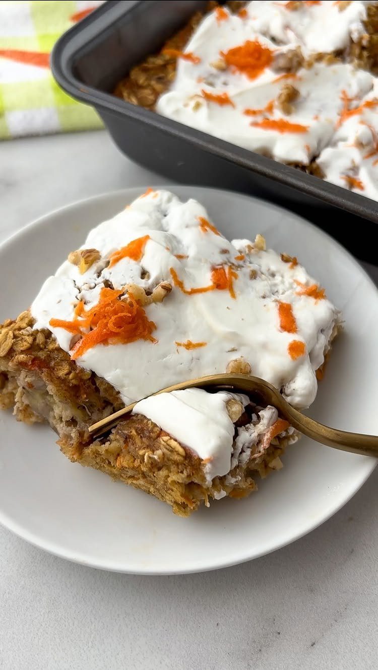 26 Oats Recipes for Snacks, from Energy Bites to Oat Crackers 26 Baked oatmeal slice with cream cheese frosting and shredded carrots on a white plate.