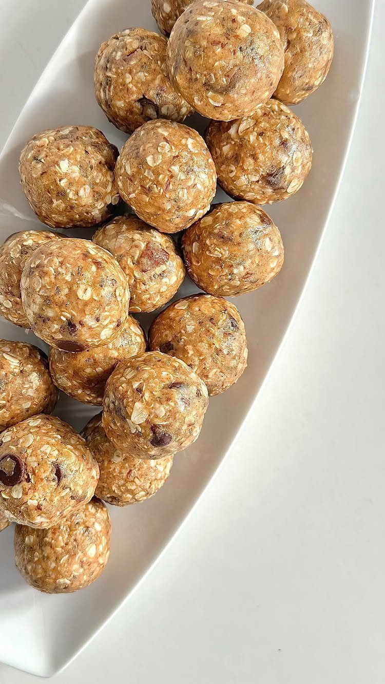 26 Oats Recipes for Snacks, from Energy Bites to Oat Crackers 22 Oat energy balls with chocolate chips arranged on a white ceramic platter.