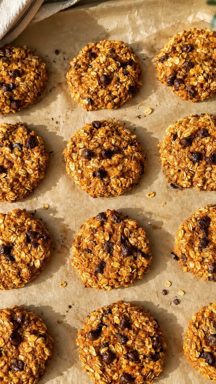 26 Oats Recipes for Snacks, from Energy Bites to Oat Crackers 19 Orange-brown oat cookies with chocolate chips resting on brown parchment paper.