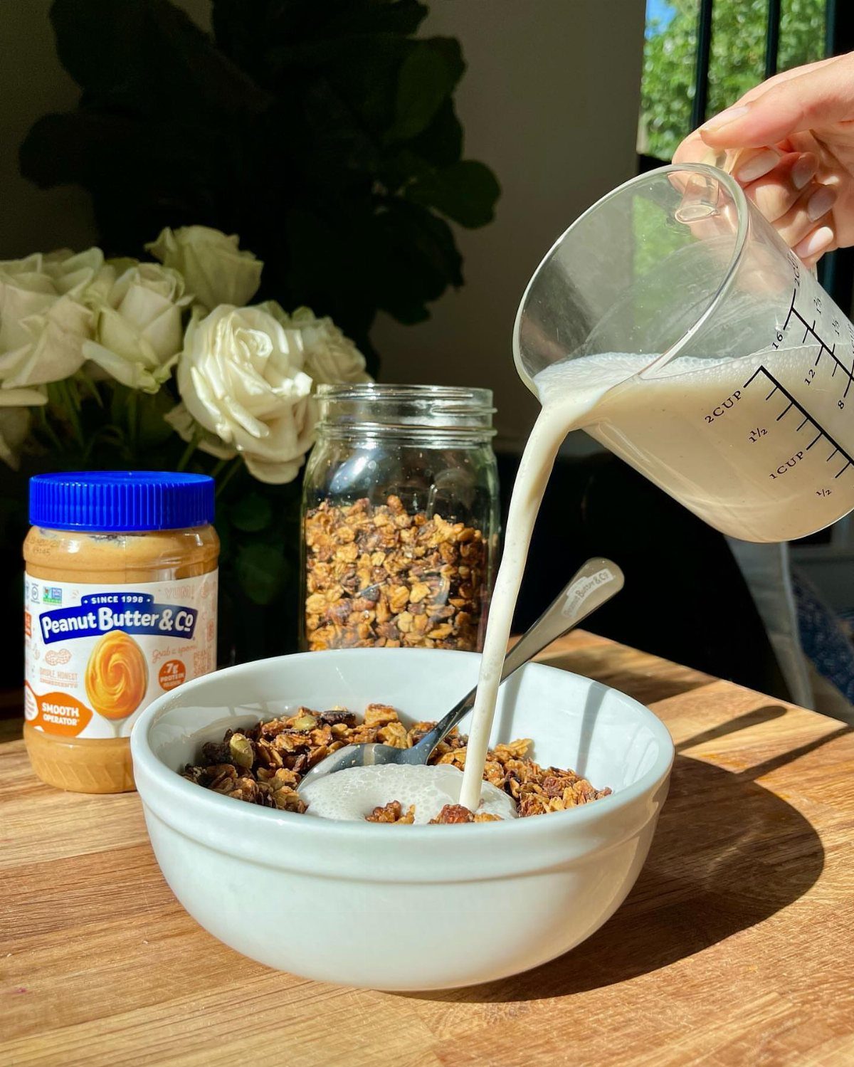 26 Oats Recipes for Snacks, from Energy Bites to Oat Crackers 9 Granola clusters in a white bowl with milk being poured from a measuring cup.