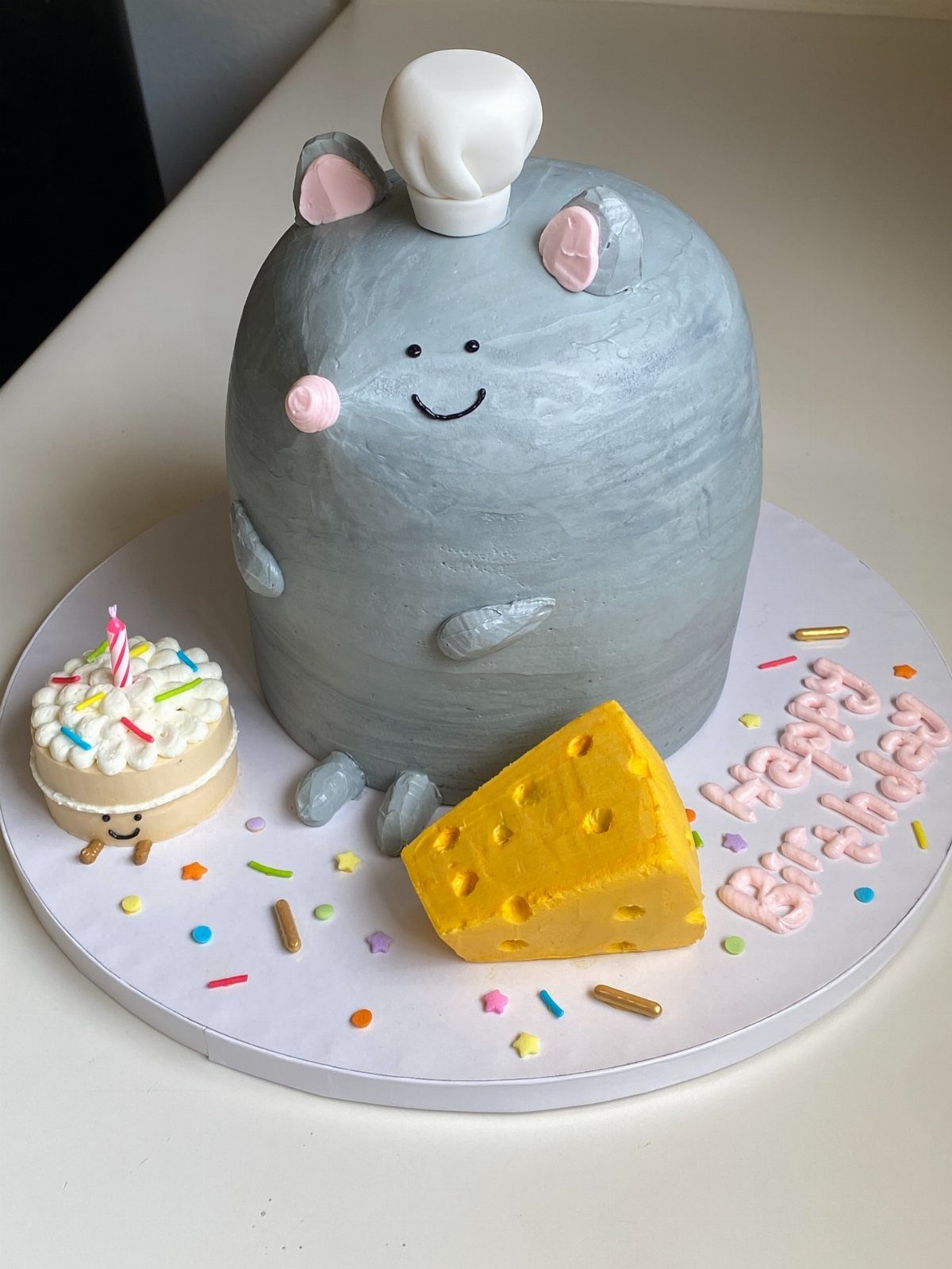 Rat Birthday Cake: 12 Ideas for Pet Rats, Pirates and Chefs 10 Grey rat-shaped cake wearing a chef hat next to a wedge of cheese.
