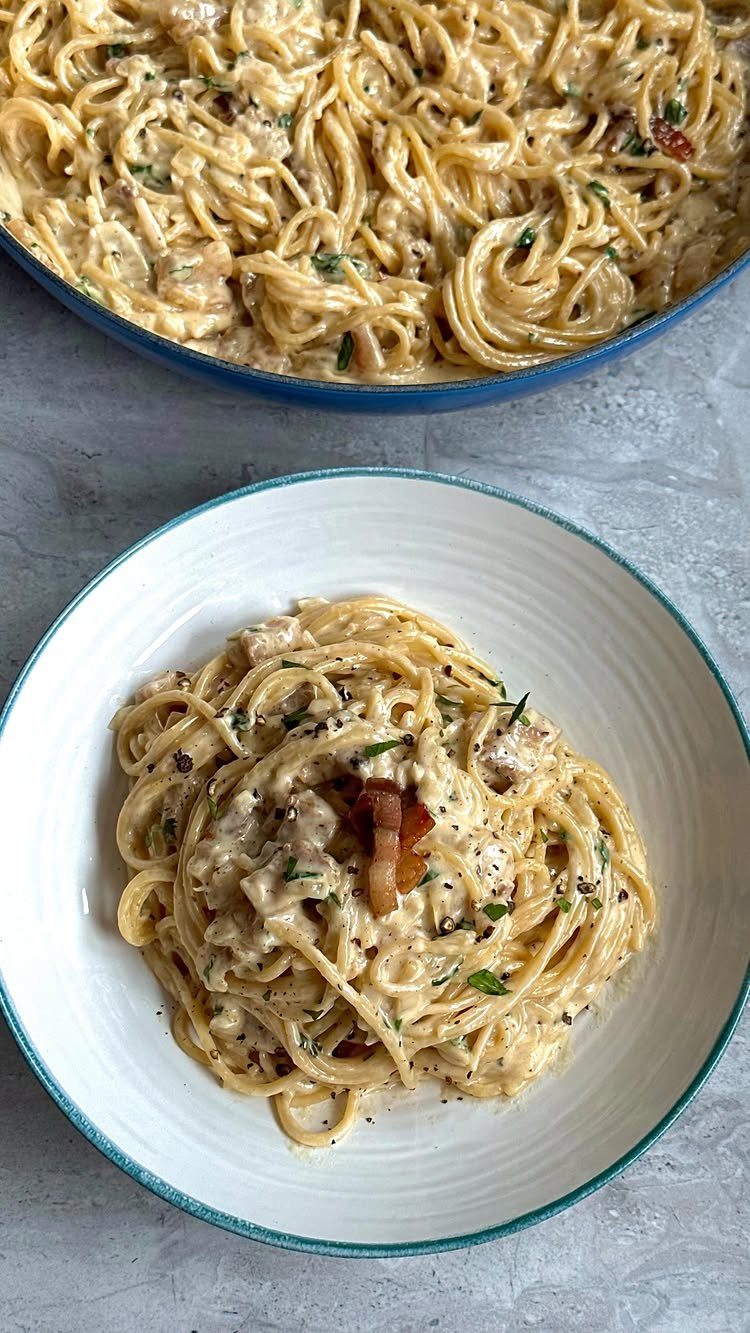 Creamy carbonara pasta with pancetta and black pepper in a white bowl.