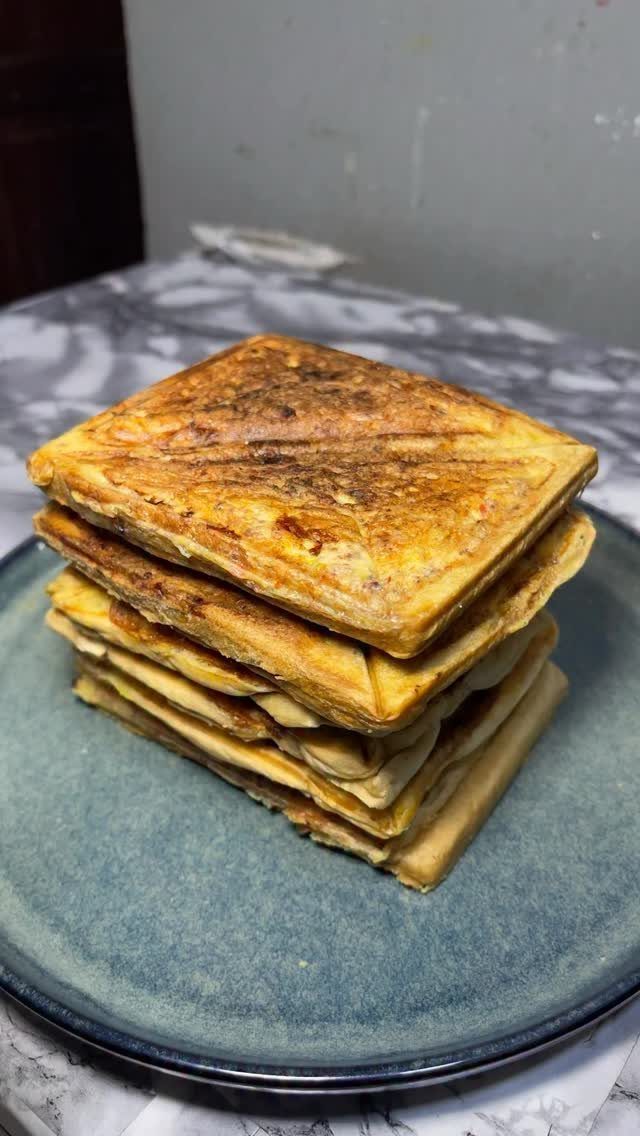 Stacked toasted sandwiches on a blue plate over a marble surface.