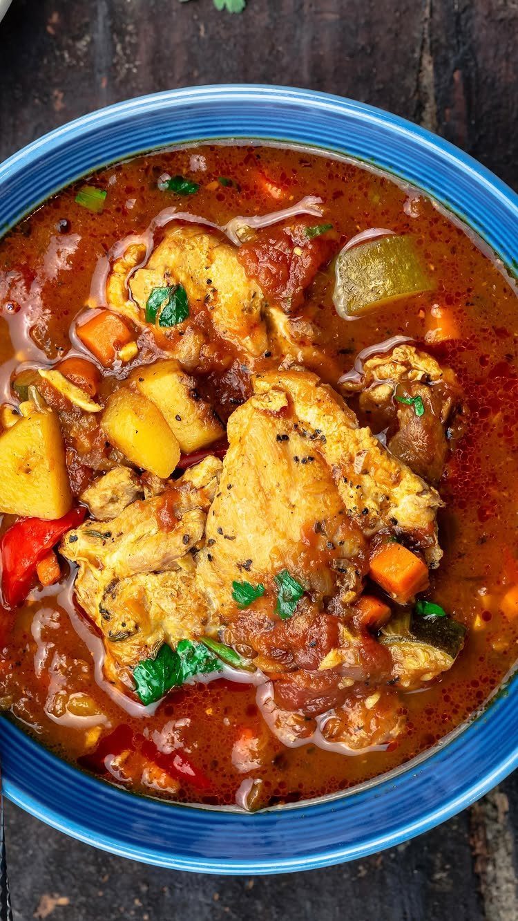 Chicken stew with potatoes and carrots in a blue bowl on wooden background
