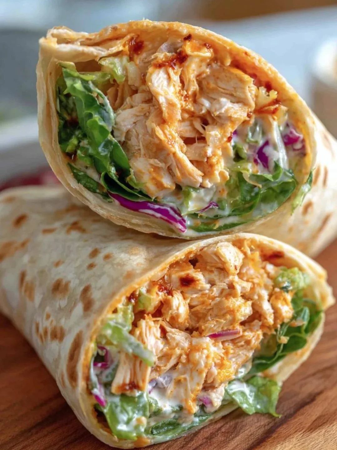 Chicken wraps with shredded meat, lettuce, and creamy sauce on a wooden board