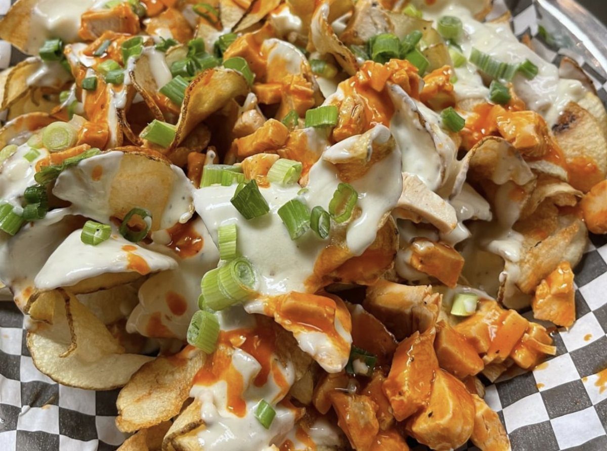Potato chips topped with buffalo chicken, white sauce, and sliced green onions.