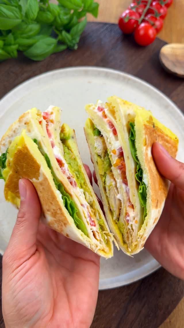 Chicken and avocado egg wraps held in hands over a white plate.