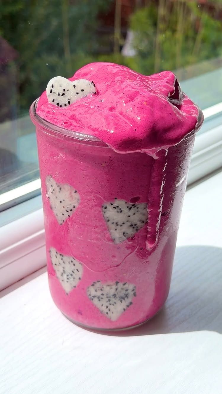 Pink smoothie in a glass jar decorated with heart-shaped dragon fruit slices.