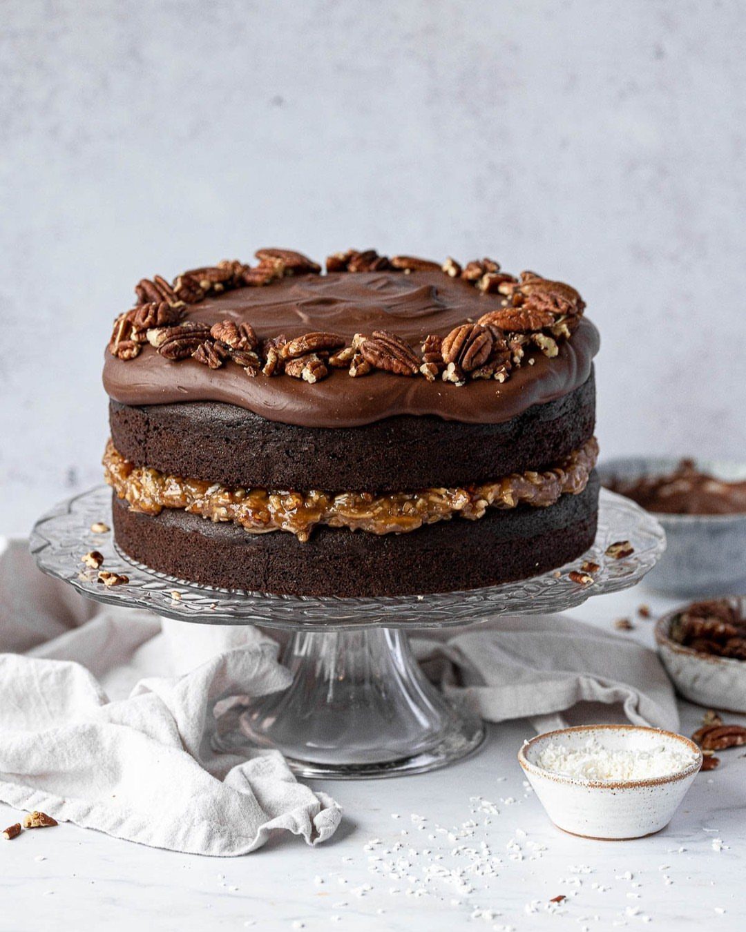 Two-layer chocolate cake with coconut pecan frosting and chocolate ganache topped with pecans.
