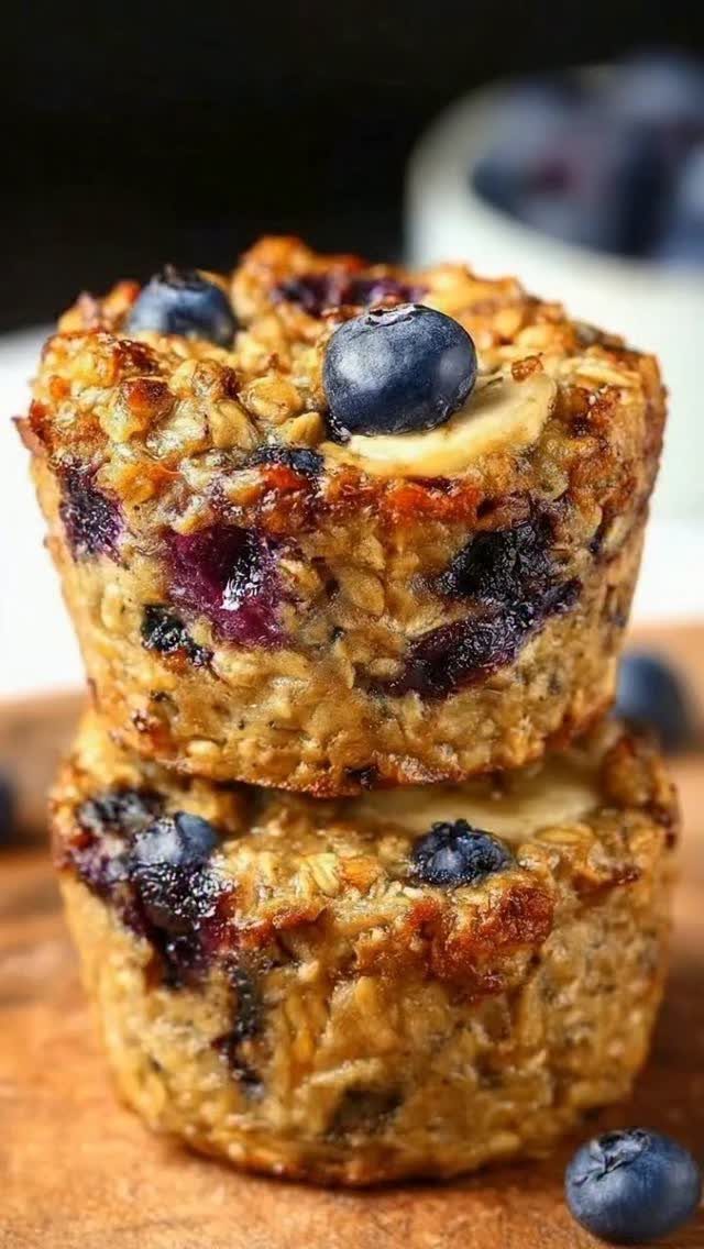 32 Ideas on What to Serve for Breakfast, From Eggs to Scones 14 Stacked baked oatmeal muffins with fresh blueberries and banana slices on wood.