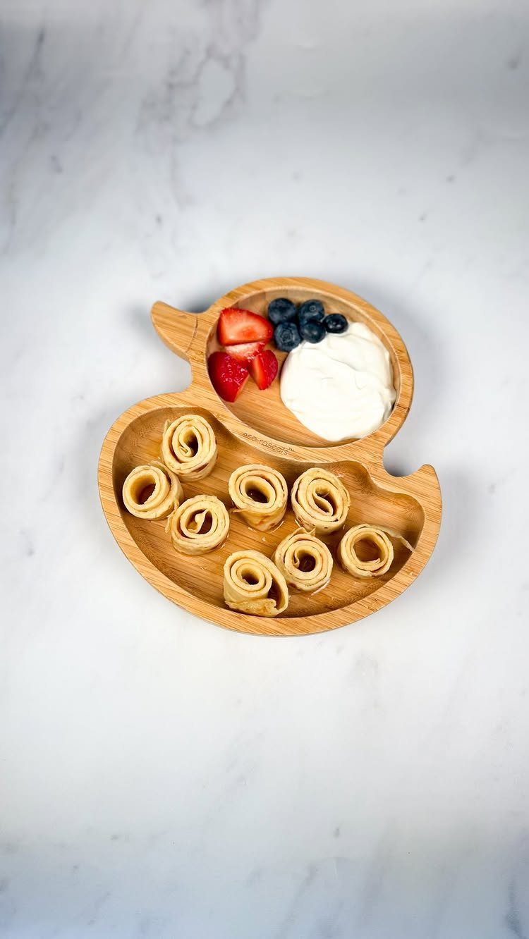 32 Ideas on What to Serve for Breakfast, From Eggs to Scones 27 Rolled crepes with yogurt, blueberries, and strawberries on an apple-shaped wooden plate.