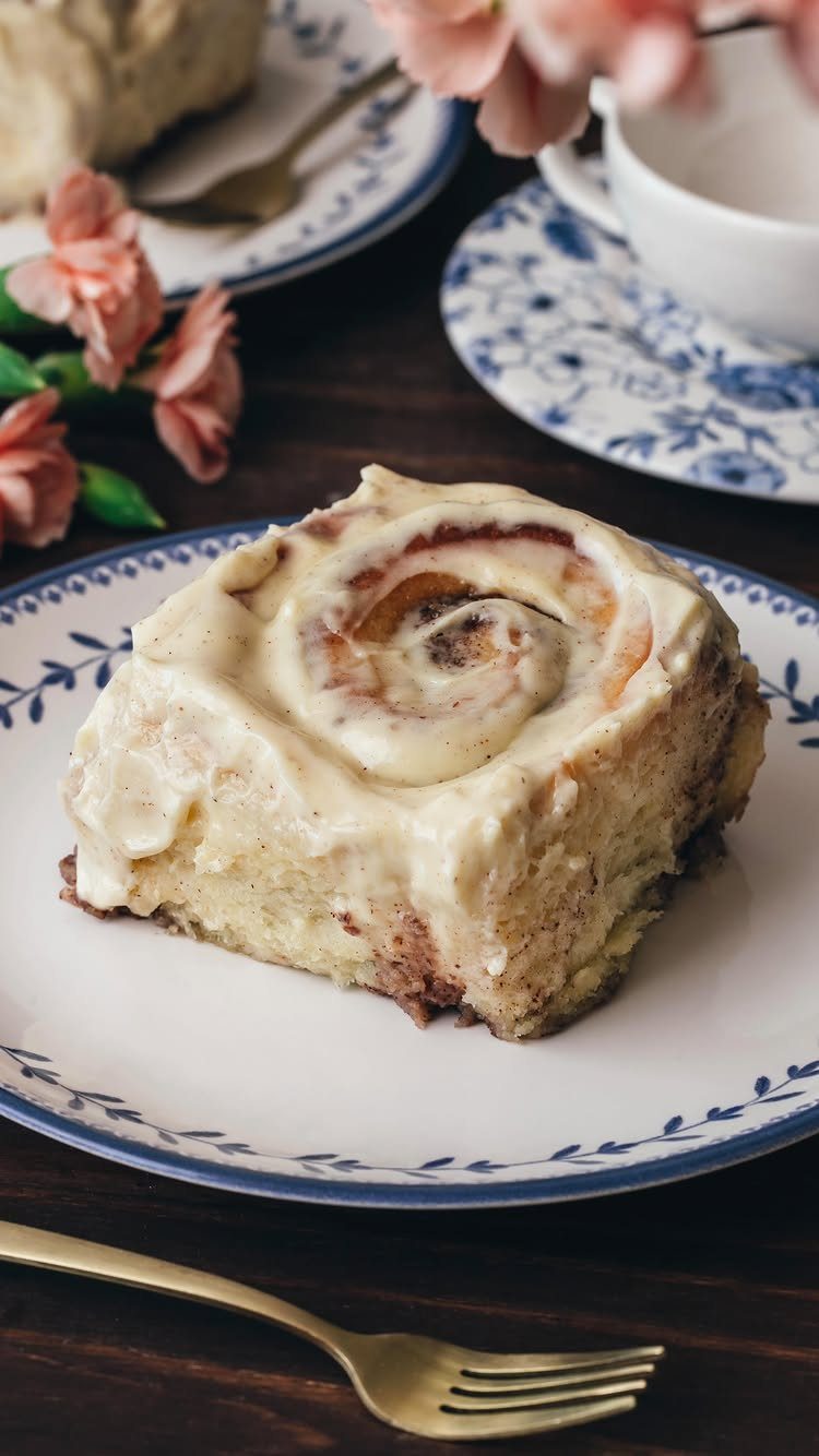 32 Ideas on What to Serve for Breakfast, From Eggs to Scones 19 Frosted cinnamon roll on a blue and white floral plate on a wooden table.