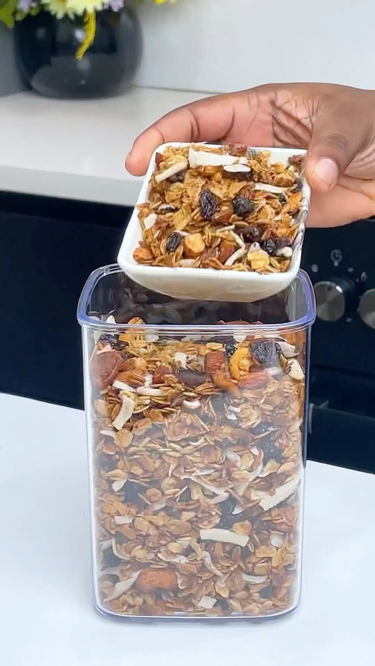 32 Ideas on What to Serve for Breakfast, From Eggs to Scones 28 Granola with nuts and coconut being poured into a clear plastic storage container.