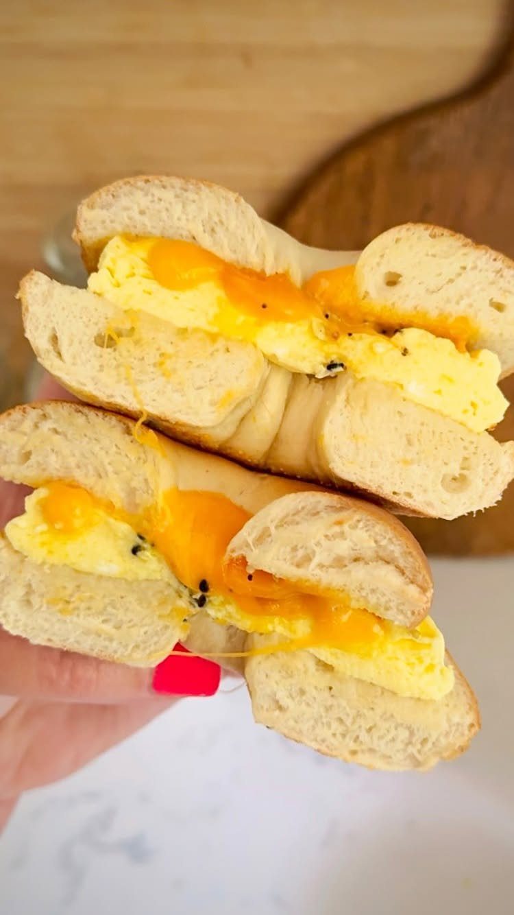 32 Ideas on What to Serve for Breakfast, From Eggs to Scones 6 Breakfast sandwich with eggs and melted cheese on a toasted bagel held by hand.