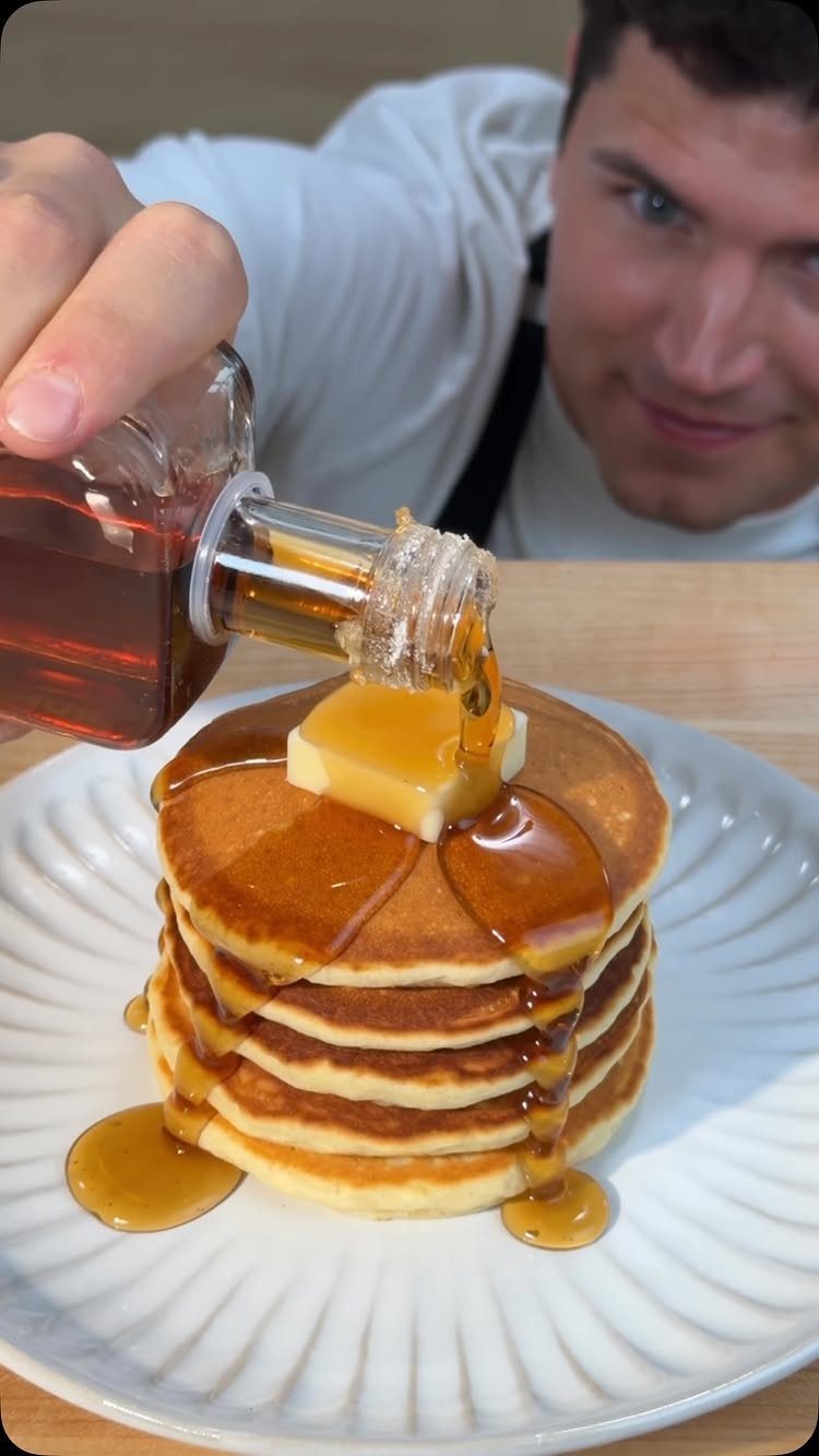 32 Ideas on What to Serve for Breakfast, From Eggs to Scones 8 Stack of pancakes with melting butter and maple syrup being poured from a dispenser.