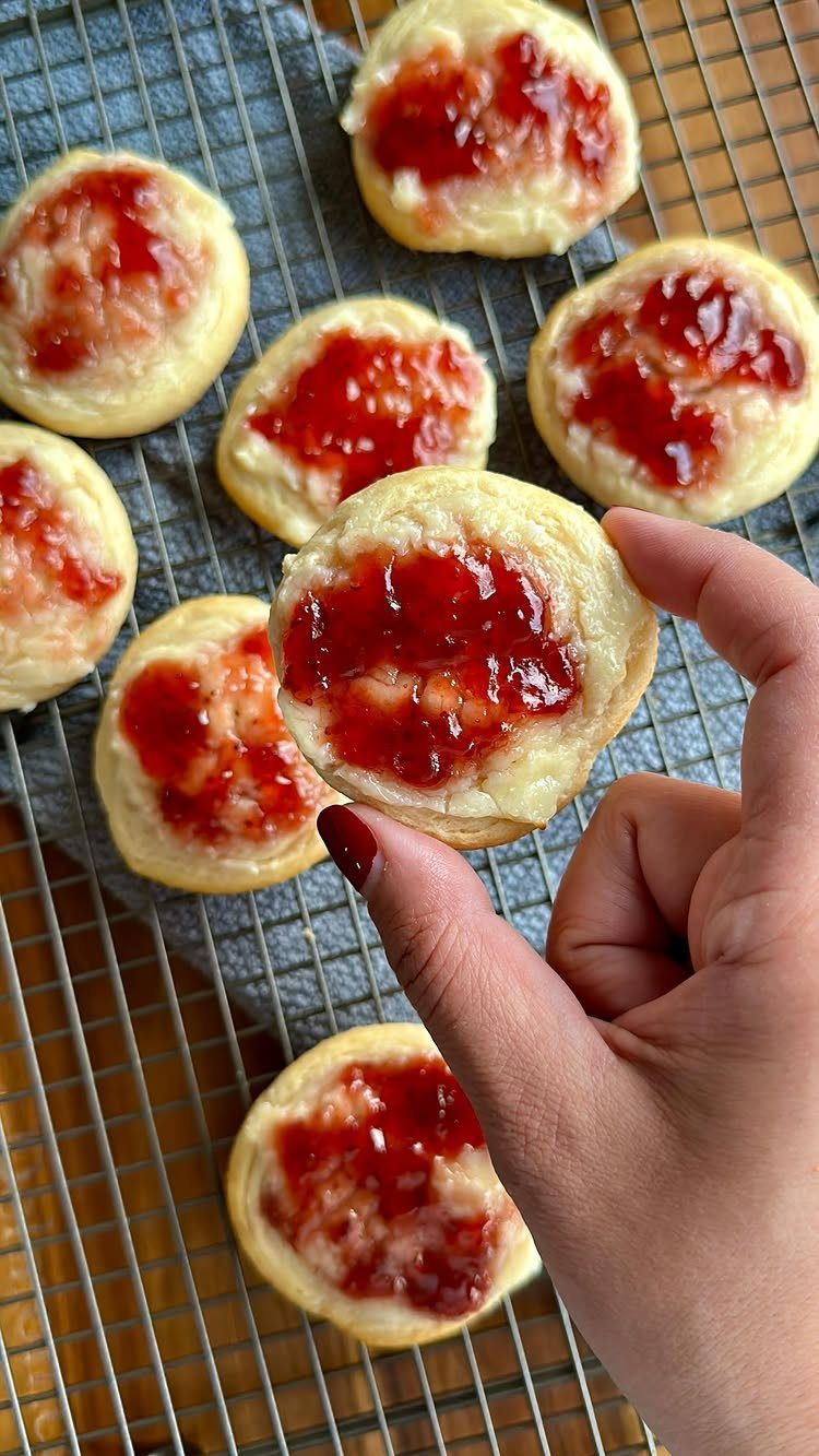 32 Ideas on What to Serve for Breakfast, From Eggs to Scones 25 Small round crescent danishes topped with cream cheese and raspberry jam on a rack.