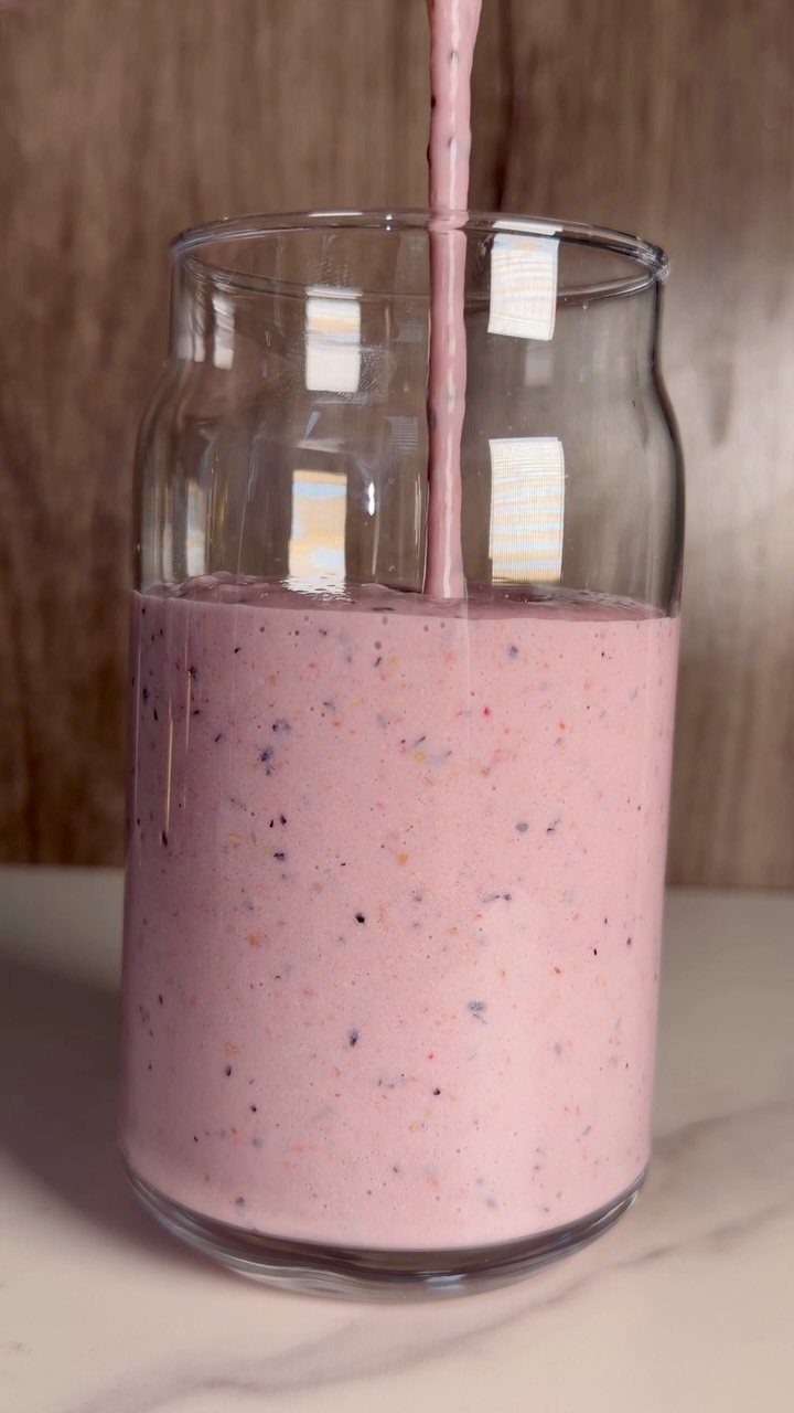 32 Ideas on What to Serve for Breakfast, From Eggs to Scones 16 Pink berry smoothie being poured into a clear glass jar on marble surface